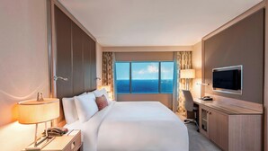 A hotel room with a large bed, a desk with a TV, a phone, and a lamp. There is a window with a view of the ocean. - Renaissance Polat Istanbul Hotel (Istanbul)