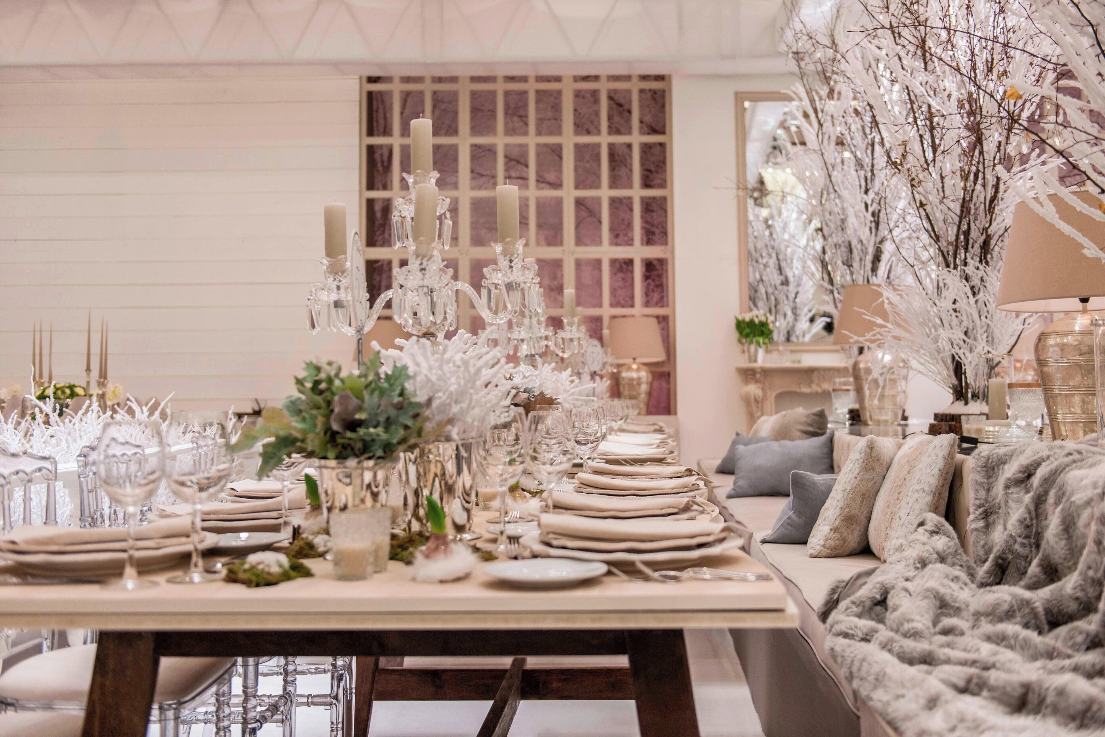 A dining area with a long table set for a meal, elegant glassware, and candle holders.