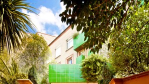 A set of terracotta steps leading to a building with a green facade and a balcony. - Hôtel Mermoz (Toulouse)