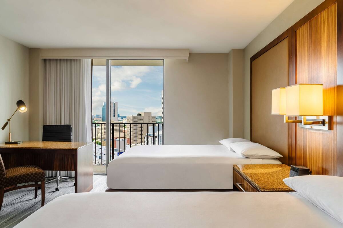 A hotel room with two beds, a desk, and a chair.