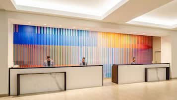 A modern reception area with a colorful vertical striped wall, a marble reception desk, and a clean, well-lit interior.