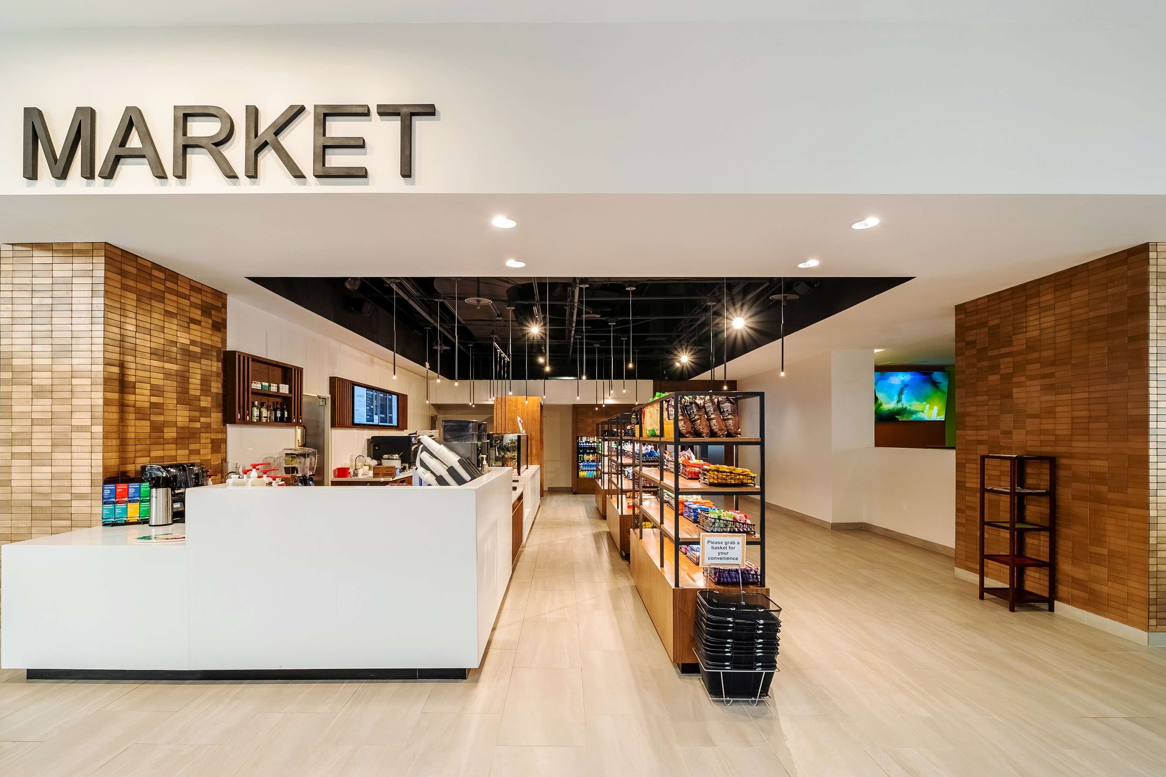 L’intérieur d’un marché moderne, avec un comptoir d’accueil, des étagères remplies de produits et un panneau indiquant un espace où l’on peut acheter des produits à emporter.