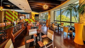 Un restaurante moderno con una zona de bar, suelo de madera y grandes ventanales con vistas a la ciudad.