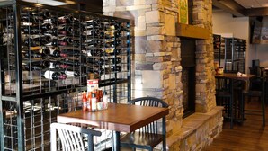 A restaurant interior with a stone fireplace, a wine rack, and a table with chairs. - Copper King Convention Center, an Ascend Collection Hotel (Butte)