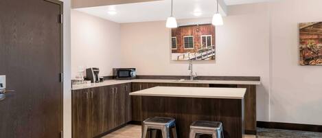 A modern kitchen with dark wood cabinets, a white countertop, and two bar stools.