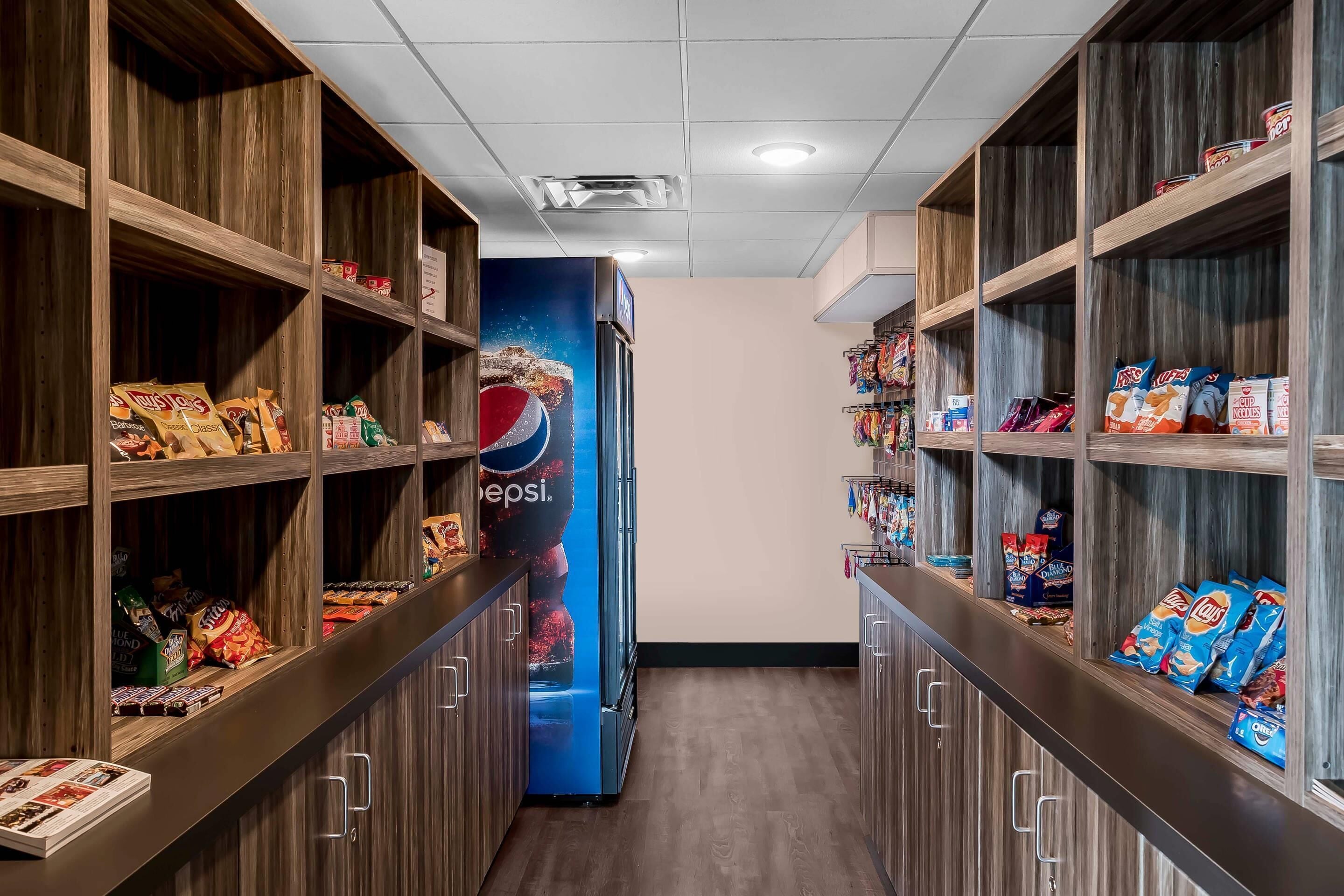 A snack aisle with shelves stocked with various snacks and a Pepsi advertisement.