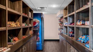A snack aisle with shelves stocked with various snacks and a Pepsi advertisement.