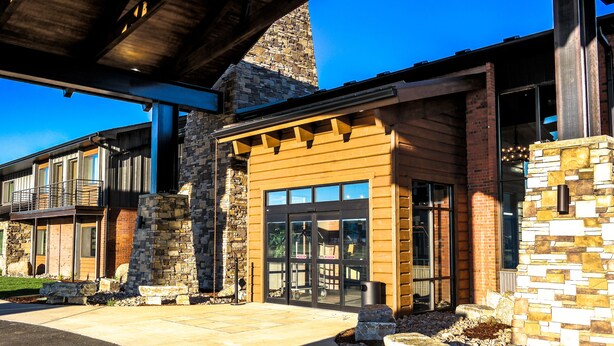 A modern building with a stone facade, large glass doors, and a covered entrance area. - Copper King Convention Center, an Ascend Collection Hotel (Butte)