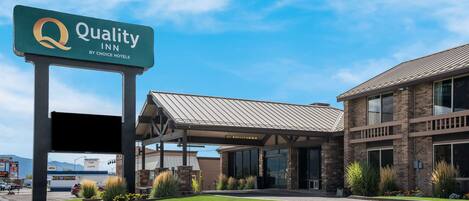 A Quality Inn by Choice Hotels with a modern building, a covered entrance, and well-maintained landscaping.