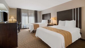 A hotel room with two beds, a desk, a TV, and a large window with curtains. - Quality Inn Richfield I-70 (Richfield)