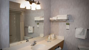 A modern bathroom with a large mirror, a sink, and a shower.