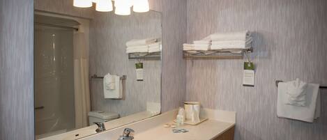 A modern bathroom with a large mirror, a sink, and a shower.