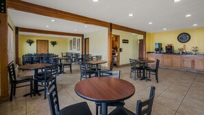 A spacious dining area with multiple tables and chairs, wooden beams on the ceiling, and a kitchen area in the background. - Quality Inn Richfield I-70 (Richfield)