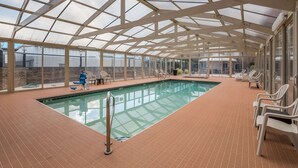 An indoor swimming pool with a glass ceiling, surrounded by lounge chairs and a brick floor. - Quality Inn Richfield I-70 (Richfield)