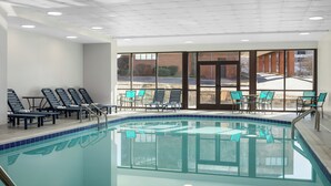 An indoor swimming pool with clear glass walls, multiple lounge chairs, and tables. - DoubleTree by Hilton Salisbury (Salisbury)