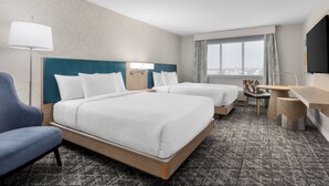 A hotel room with two beds, a desk, a chair, a TV, and a window with a city view. - DoubleTree by Hilton Salisbury (Salisbury)