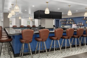 A bar area with stools, a counter, and hanging pendant lights. - DoubleTree by Hilton Salisbury (Salisbury)