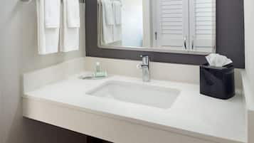 Un baño con un lavamanos blanco, un espejo y dos toallas colgadas en un toallero.