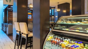 A Starbucks café with seating, a display case with beverages, and a television in the background.