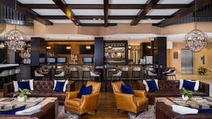 A spacious lobby with leather sofas, a bar area, and a high ceiling with exposed beams.