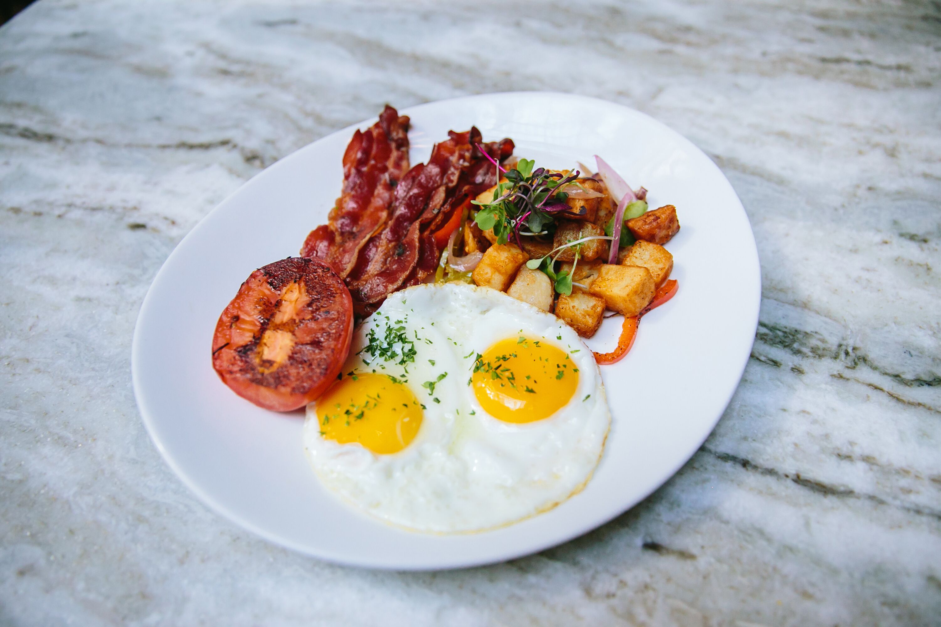 Un plato de comida con huevos, tocino y papas.