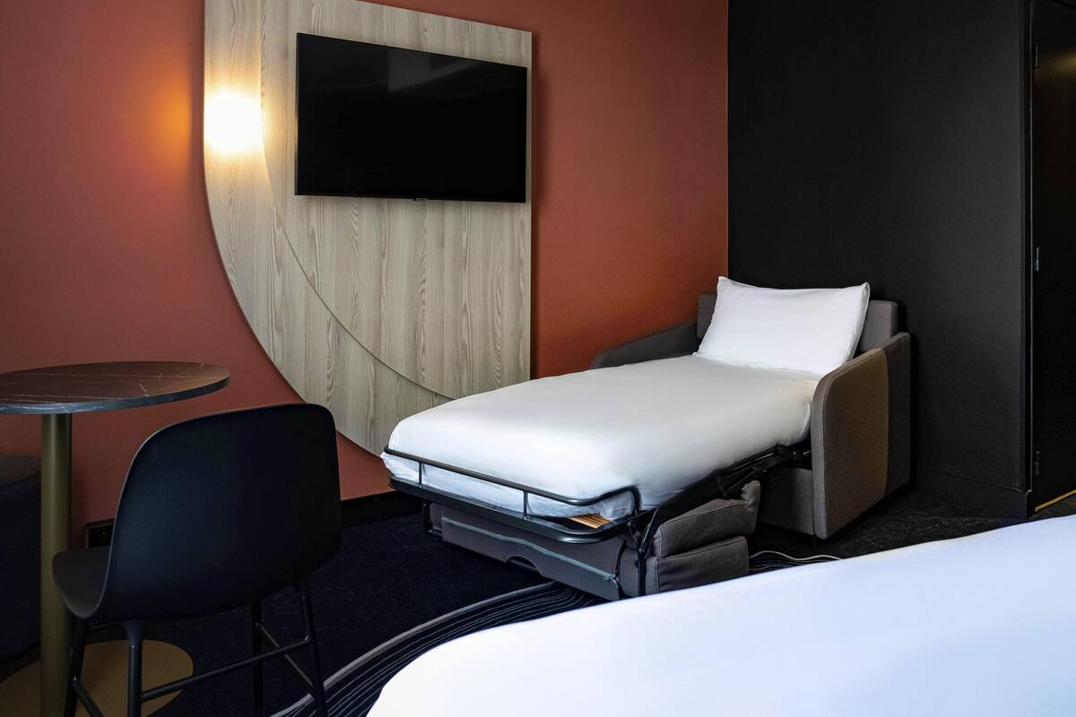 Ein kleines Hotelzimmer mit einem Einzelbett, einem Tisch und einem Stuhl.