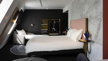 A modern hotel room with a large bed, a desk, a chair, and a small round table.