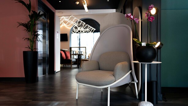 A modern lounge area with a contemporary chair, a potted plant, and a decorative light fixture. - ibis Styles Paris Porte de Versailles - Mairie d'Issy (Issy-les-Moulineaux)
