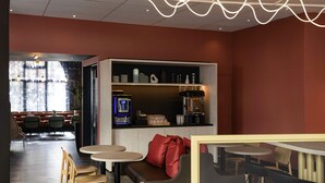 A modern cafe with a seating area, a coffee machine, and a bookshelf. - ibis Styles Paris Porte de Versailles - Mairie d'Issy (Issy-les-Moulineaux)