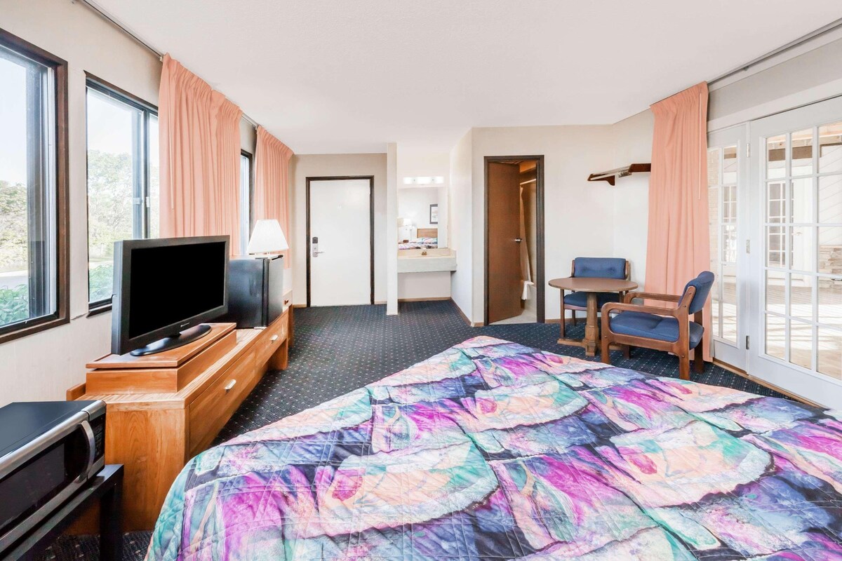 Une chambre d’hôtel avec un lit, une télévision, un bureau et une chaise.