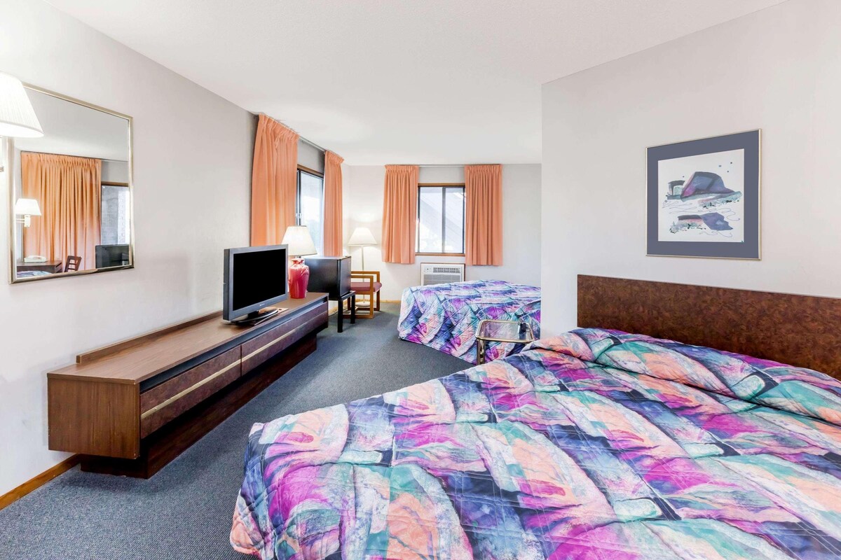 Une chambre d’hôtel avec un lit, un bureau, une télévision et une chaise.