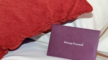 Una cama con un almohadón rojo y una tarjeta morada que dice 'Message Personnel'.