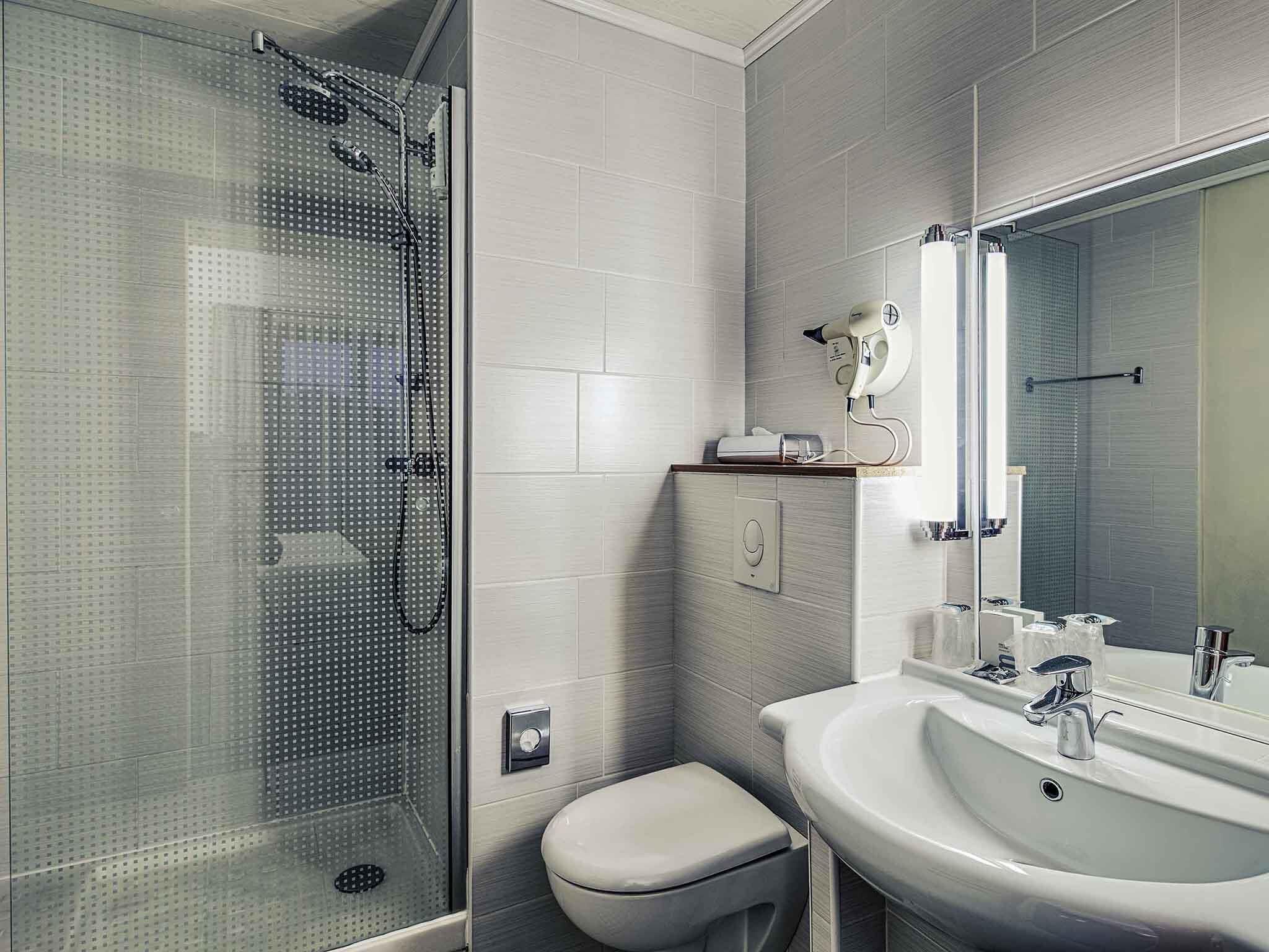 A modern bathroom with a glass shower enclosure, a toilet, and a sink with a mirror.