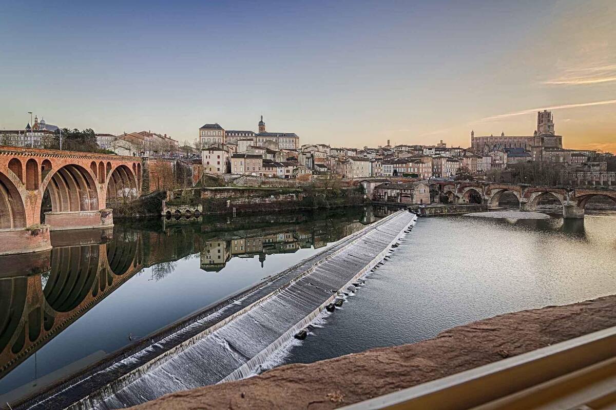 A river with a bridge and buildings in the background.
