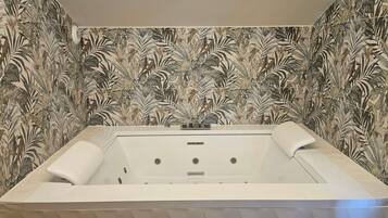 A bathroom with a large bathtub, a shower, and a wall with a leaf pattern.