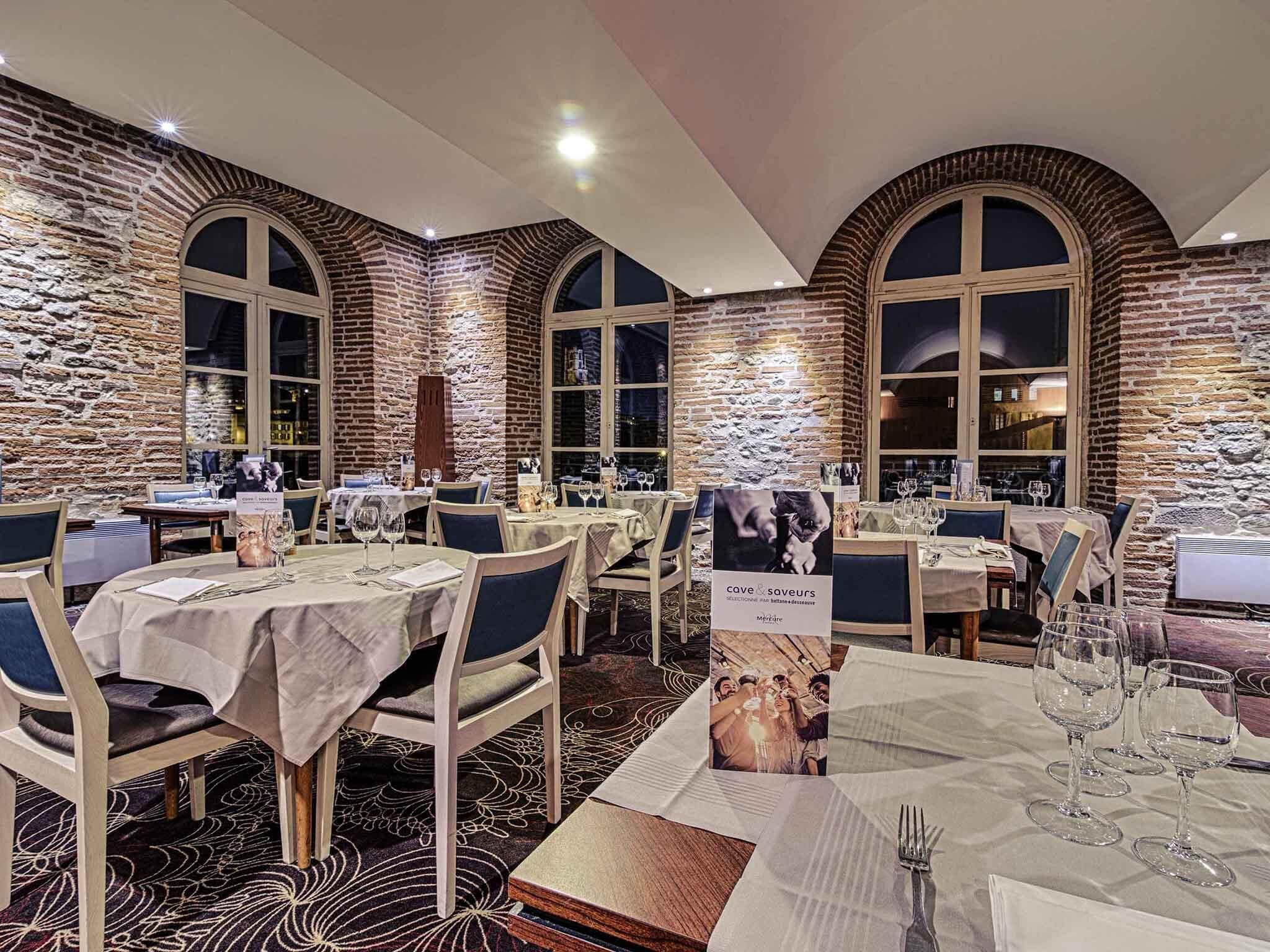 A restaurant with brick walls, arched windows, and tables set for dining.