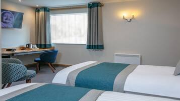 A hotel room with two beds, a desk with a chair, a TV, and a window with curtains.