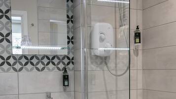 A modern bathroom with a glass-enclosed shower, a pedestal sink, and a toilet.