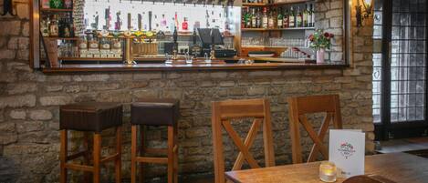 A bar area with stools, a wooden table, and a wine list sign.