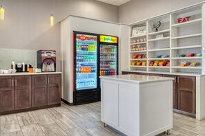 A kitchenette area with a refrigerator stocked with beverages, a coffee machine, and a pantry shelf with snacks. - Best Western Fairfax (Fairfax)