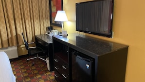 A hotel room with a desk, chair, television, and a bed. - Ramada by Wyndham Rochelle Park Near Paramus (Rochelle Park)