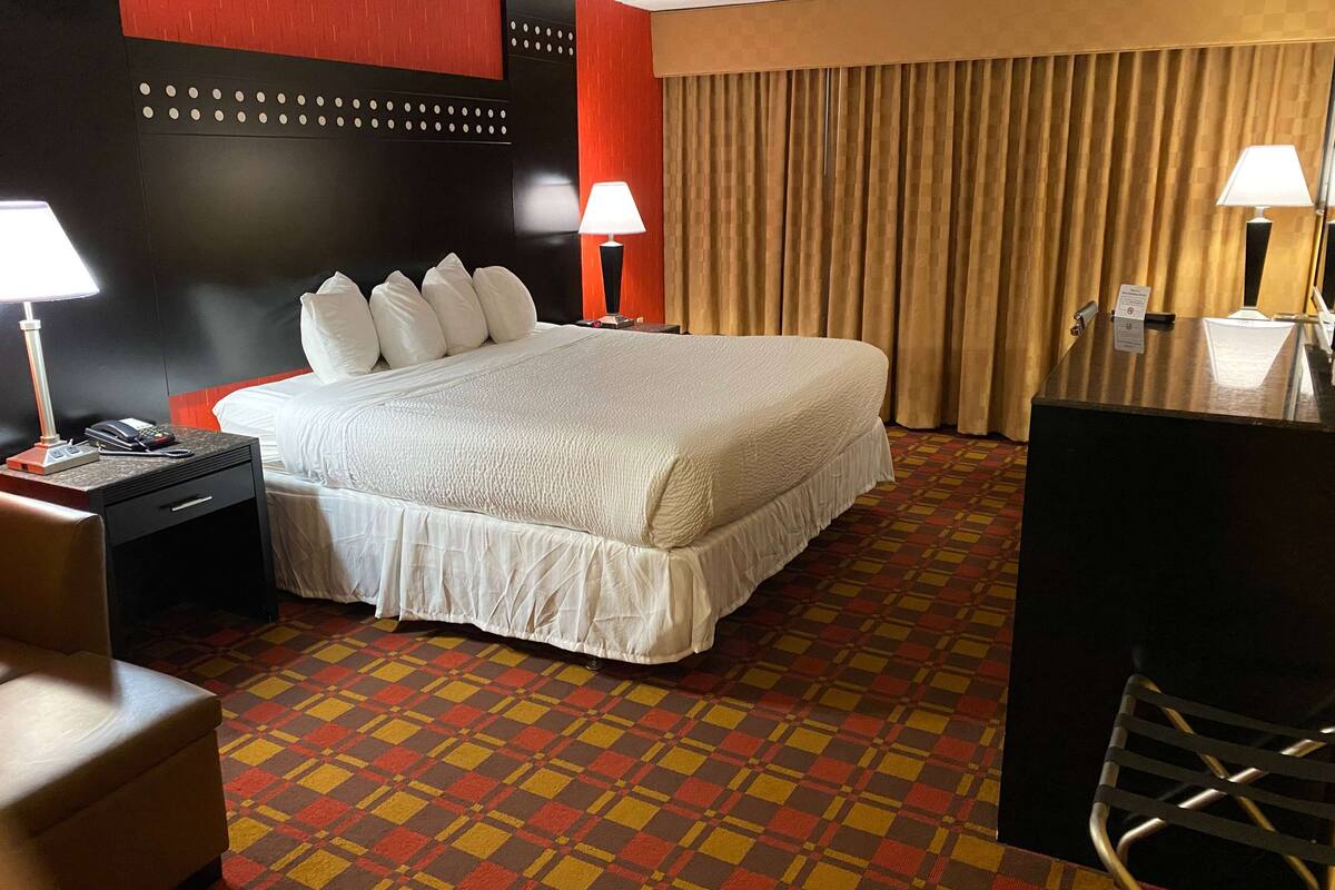 A hotel room with a large bed, two bedside tables, a desk, and a chair.