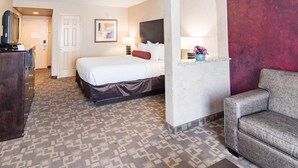 A hotel room with a bed, a dresser, a sofa, and a wall-mounted TV. - Clarion Inn Elmhurst - Oak Brook near I-88, I-290, I-294 (Elmhurst)