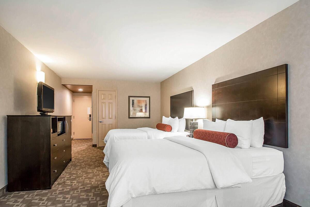 A hotel room with a large bed, a dresser, a television, and a framed picture on the wall.