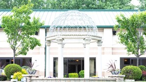 A building with a central pavilion, surrounded by well-maintained landscaping and trees. - Clarion Inn Elmhurst - Oak Brook near I-88, I-290, I-294 (Elmhurst)