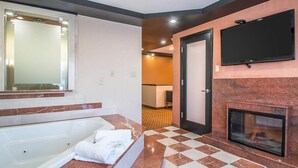 A modern bathroom with a large bathtub, a flat-screen TV mounted above the fireplace, and a checkered floor. - Clarion Inn Elmhurst - Oak Brook near I-88, I-290, I-294 (Elmhurst)