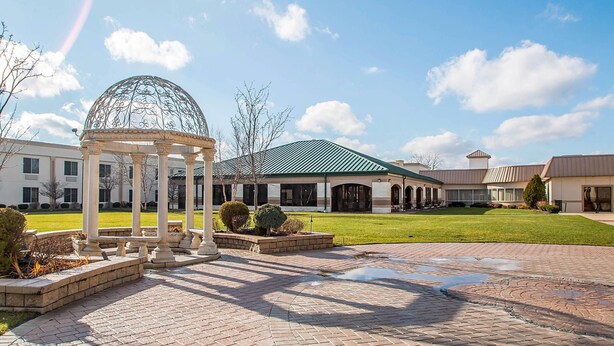 A gazebo with a dome and columns, a brick pathway, and a building with a green roof in the background. - Clarion Inn Elmhurst - Oak Brook near I-88, I-290, I-294 (Elmhurst)