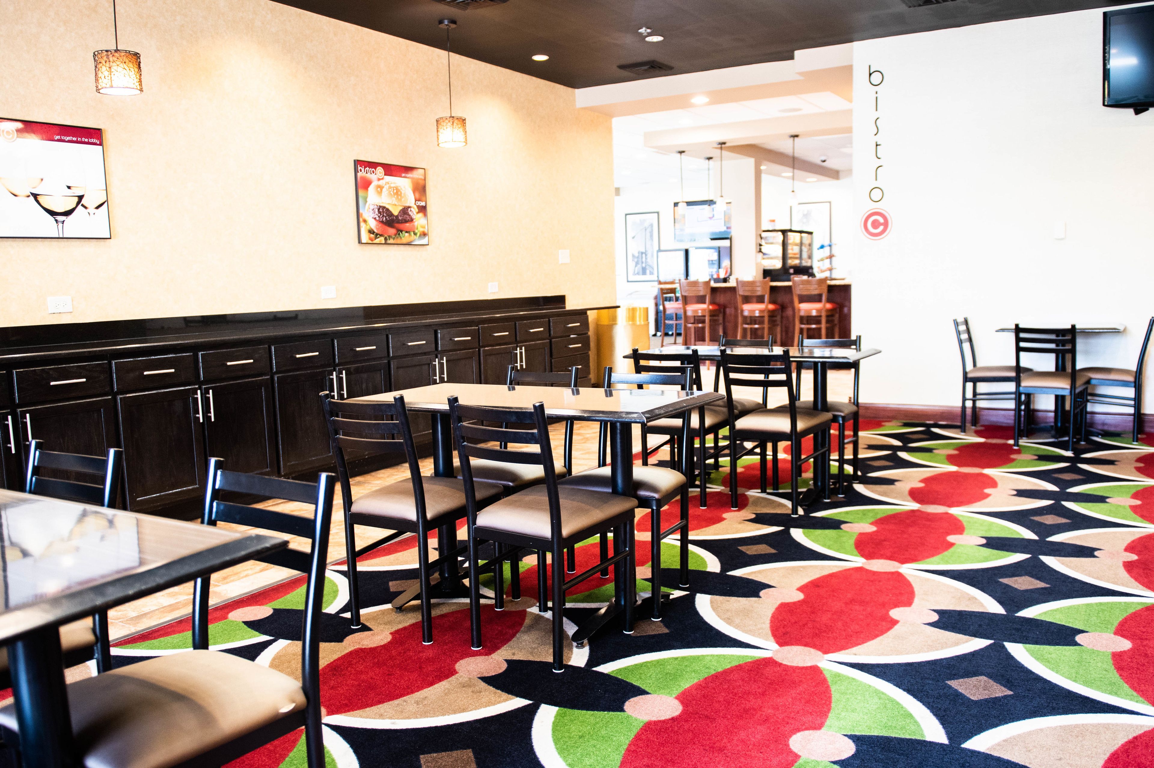 A restaurant interior with booths and tables, a patterned carpet, and wall decorations.