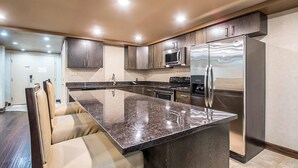 A modern kitchen with dark wood cabinets, stainless steel appliances, and a marble countertop. - Clarion Inn Elmhurst - Oak Brook near I-88, I-290, I-294 (Elmhurst)