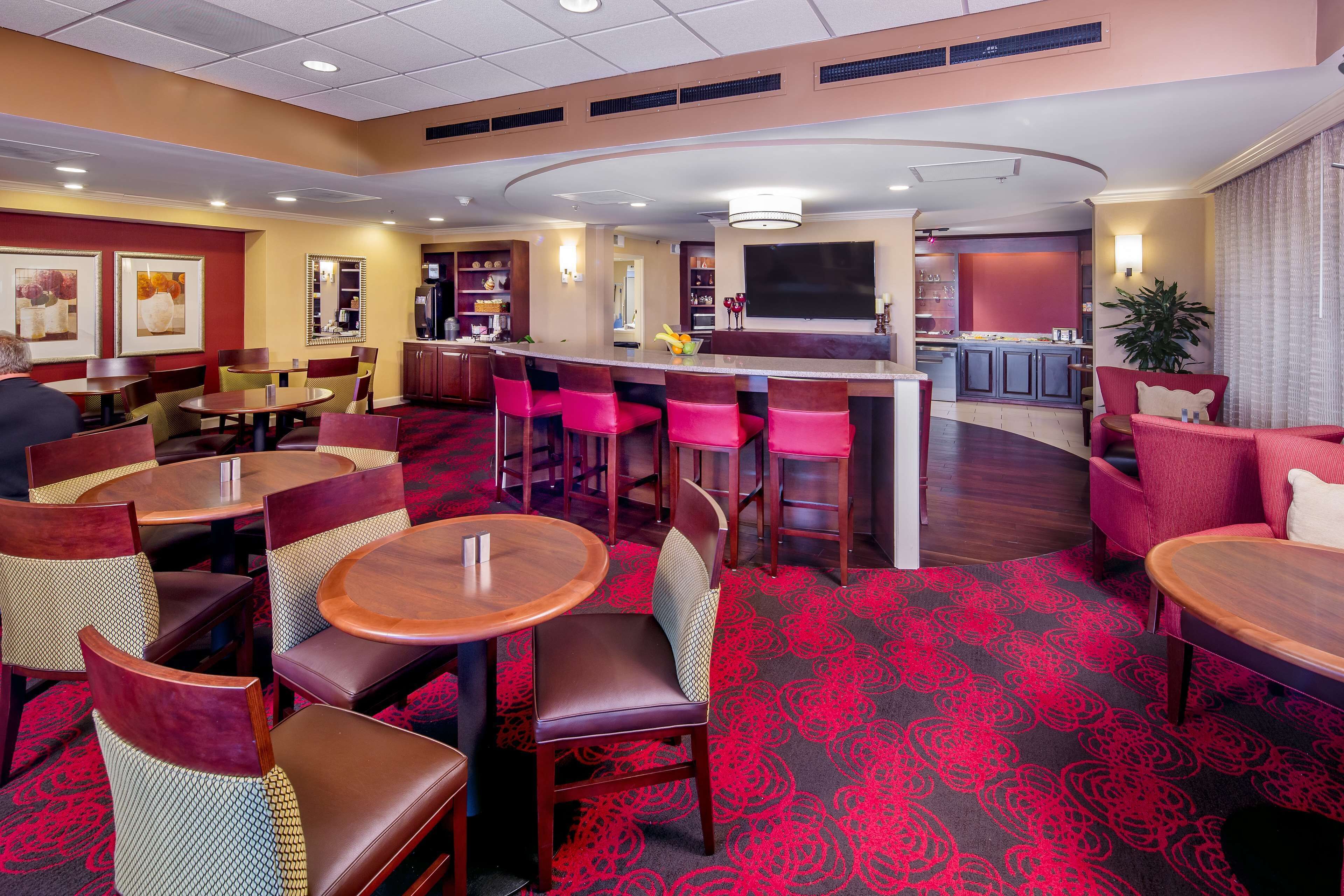 A hotel lobby with round tables, bar area, and seating.